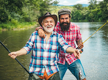 man and son smiling  holding fishing  rods in river