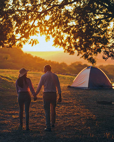 couple walking back to tent at sunset