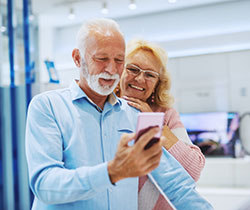 Retired couple Shopping for electronics holding a cell phone
