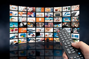 Home Entertainment tv channels on large TV with hand holding remote control