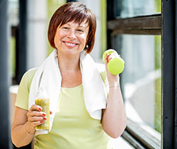 woman holding healthy drink and lifting a weight